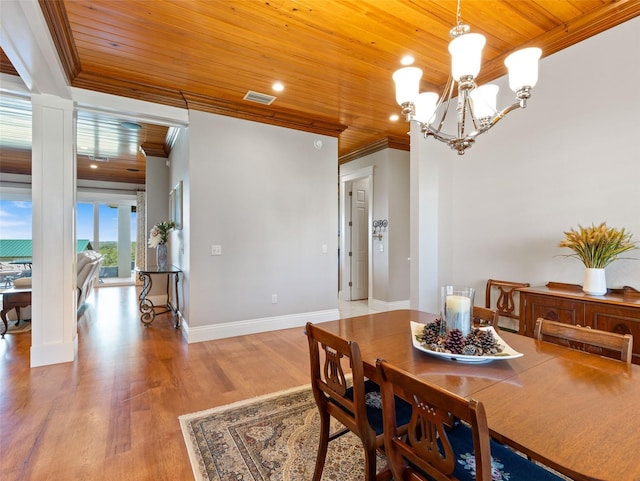 dining area with an inviting chandelier, crown molding, wooden ceiling, hardwood / wood-style flooring, and decorative columns