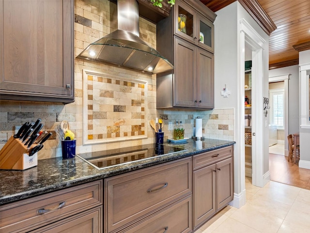 kitchen featuring wall chimney range hood, decorative backsplash, dark stone counters, and black electric stovetop