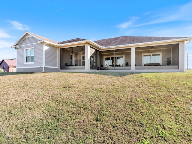 back of property with a lawn, a sunroom, and ceiling fan