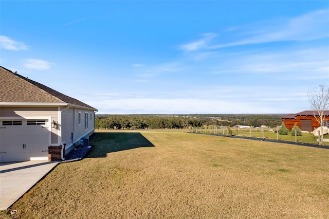 view of yard with a garage and a rural view