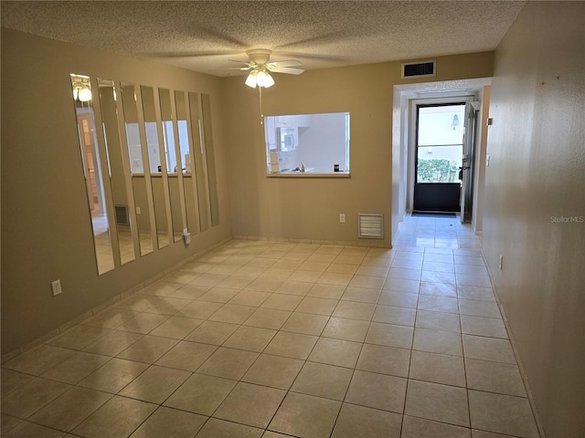 tiled spare room with ceiling fan and a textured ceiling