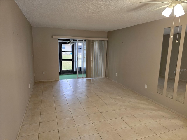 empty room with ceiling fan, light tile patterned floors, and a textured ceiling