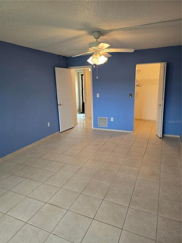 tiled empty room featuring ceiling fan and a textured ceiling