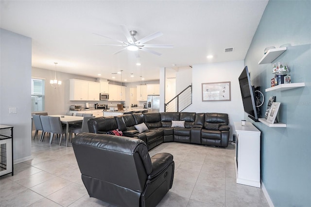 tiled living room featuring ceiling fan with notable chandelier