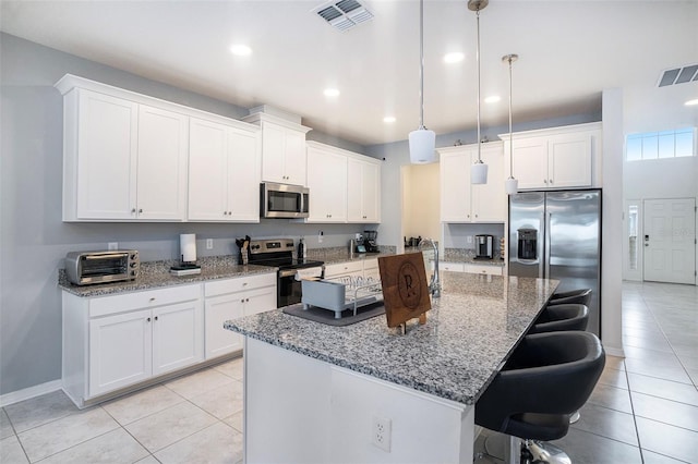 kitchen with a kitchen bar, white cabinetry, a center island with sink, appliances with stainless steel finishes, and pendant lighting