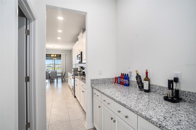 kitchen featuring white cabinetry, light stone countertops, stainless steel appliances, and light tile patterned flooring