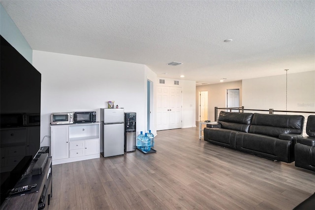 living room with a textured ceiling and light wood-type flooring