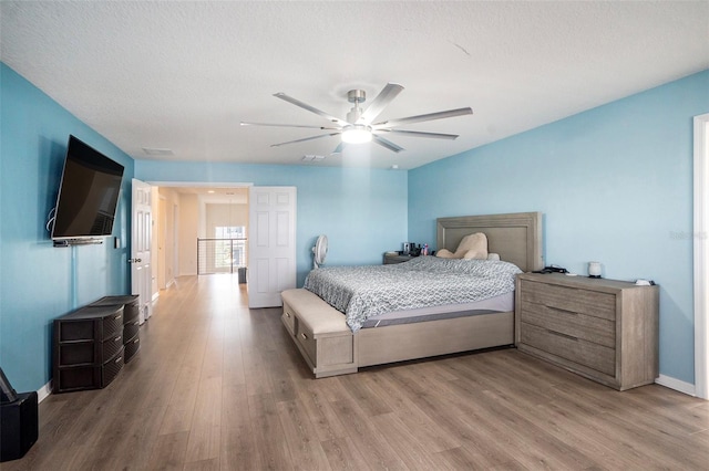 bedroom with ceiling fan, a textured ceiling, and light wood-type flooring