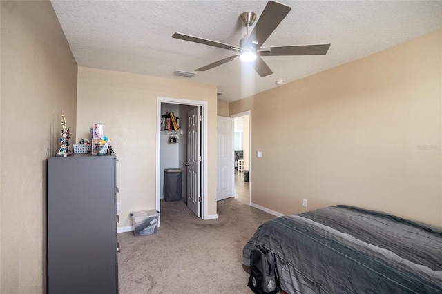 bedroom featuring ceiling fan, light carpet, and a textured ceiling