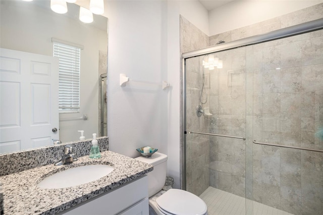 bathroom with vanity, toilet, and a shower with door