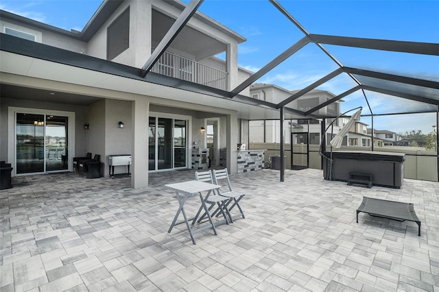 view of patio with a hot tub, a balcony, and glass enclosure