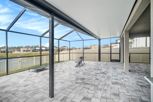 view of patio / terrace featuring a water view and glass enclosure