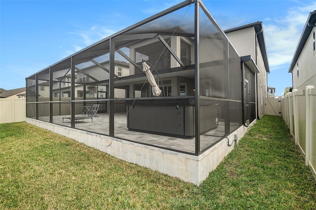 back of house with a lanai, a patio area, a hot tub, and a lawn