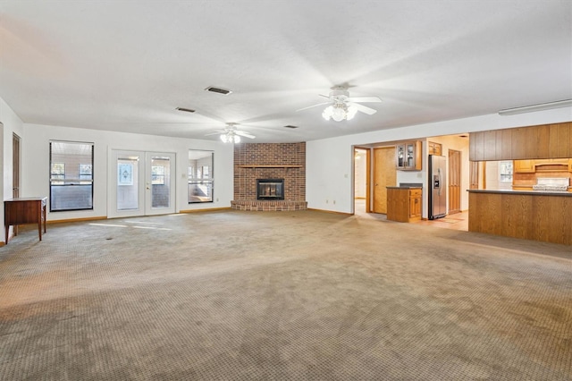 unfurnished living room featuring light carpet, a fireplace, and ceiling fan