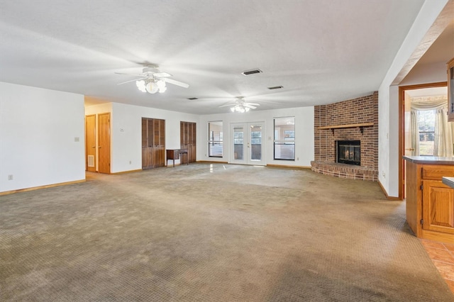 unfurnished living room featuring ceiling fan, light colored carpet, and a fireplace