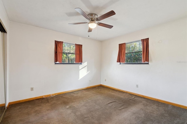 empty room featuring a wealth of natural light, ceiling fan, and carpet