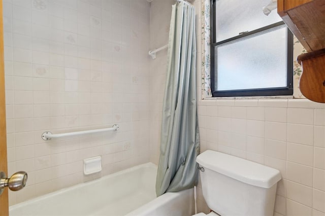 bathroom featuring tile walls, shower / tub combo, and toilet