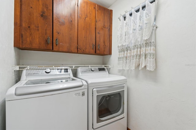 clothes washing area with cabinets and washing machine and dryer