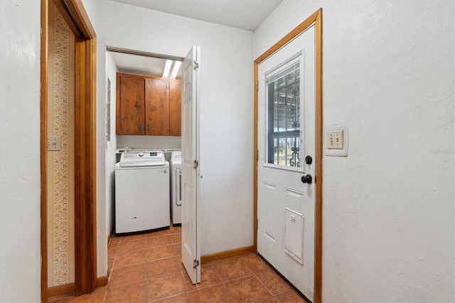 clothes washing area featuring cabinets, washing machine and clothes dryer, and tile patterned floors