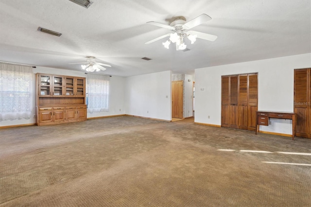 unfurnished living room with carpet flooring, a textured ceiling, and ceiling fan