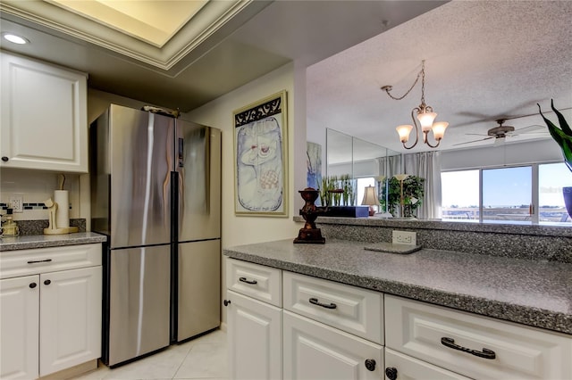 kitchen featuring light tile patterned floors, stainless steel refrigerator, white cabinetry, hanging light fixtures, and a textured ceiling