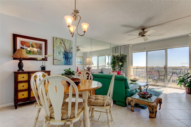 tiled dining room featuring ceiling fan with notable chandelier and a textured ceiling