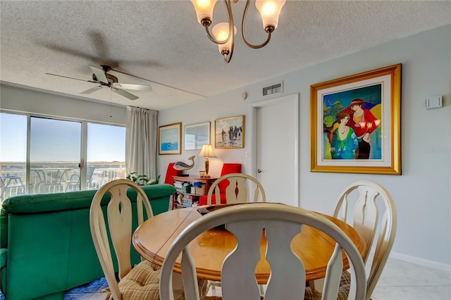 dining space featuring ceiling fan with notable chandelier and a textured ceiling