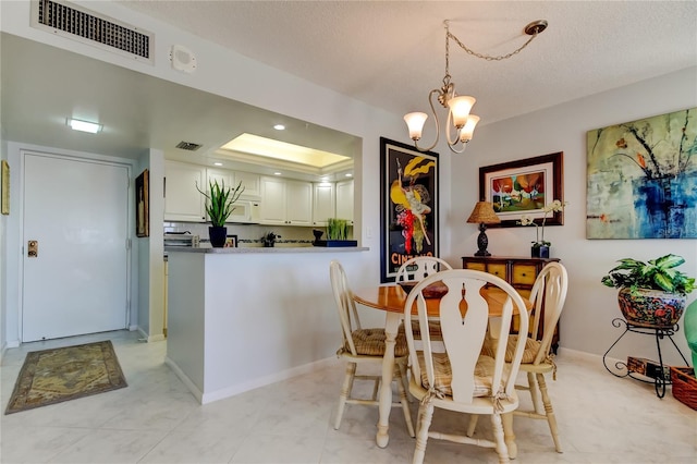 dining space with a notable chandelier, a tray ceiling, and a textured ceiling