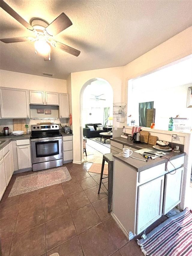 kitchen featuring ceiling fan, a textured ceiling, stainless steel electric stove, and white cabinets