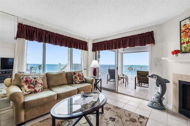 living room featuring a water view, light tile patterned floors, a textured ceiling, and a fireplace