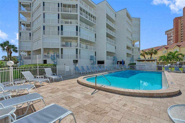 community pool with a patio area and fence