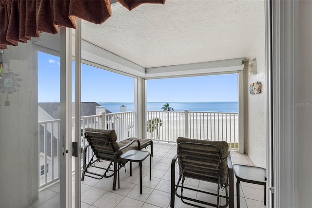 sunroom / solarium with a water view and a beach view