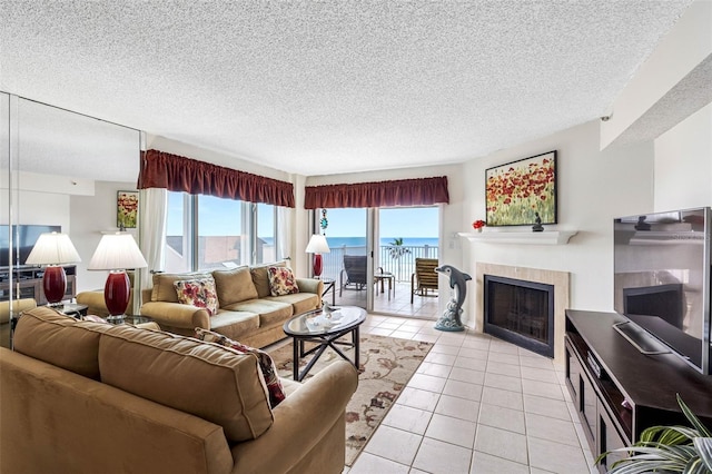 living area with a textured ceiling, a tiled fireplace, and light tile patterned floors