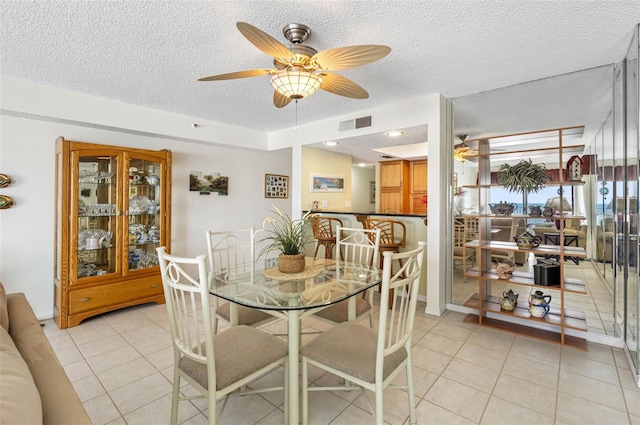 dining area featuring visible vents, ceiling fan, a textured ceiling, and light tile patterned floors