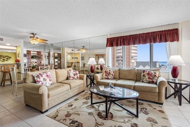 living area with a ceiling fan, visible vents, a textured ceiling, and light tile patterned floors