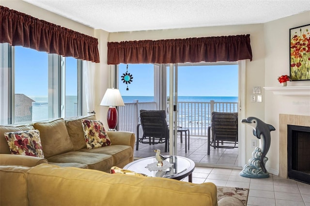 living room with a water view, light tile patterned floors, a textured ceiling, and a tiled fireplace