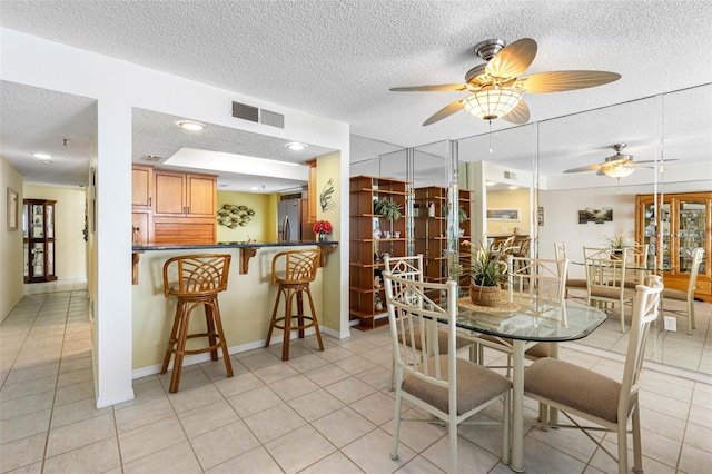 dining space with visible vents, a textured ceiling, baseboards, and light tile patterned floors