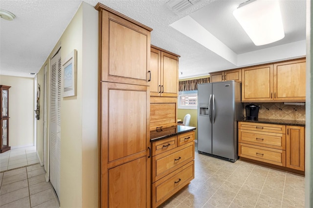 kitchen with a textured ceiling, stainless steel fridge, and decorative backsplash