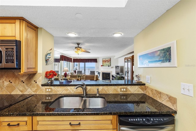 kitchen featuring dishwashing machine, stainless steel microwave, dark stone countertops, and a sink