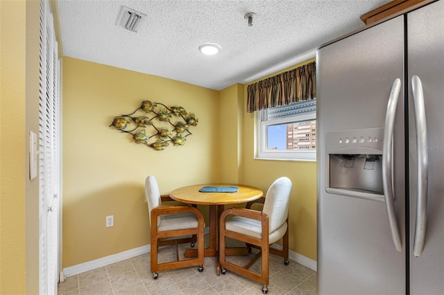 dining area with baseboards, visible vents, and a textured ceiling