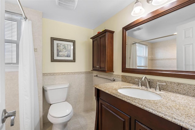 bathroom featuring a wainscoted wall, tile walls, visible vents, toilet, and vanity