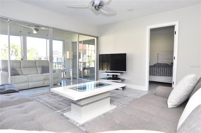 living room with ceiling fan and a textured ceiling