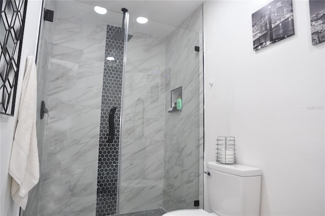 bathroom featuring tiled shower and toilet