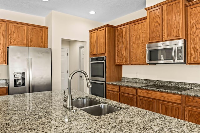 kitchen featuring appliances with stainless steel finishes, sink, a textured ceiling, and dark stone counters