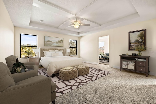 carpeted bedroom with multiple windows, a tray ceiling, coffered ceiling, and ceiling fan