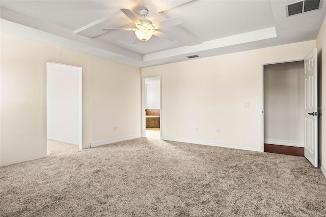 spare room with ceiling fan, carpet flooring, and a raised ceiling