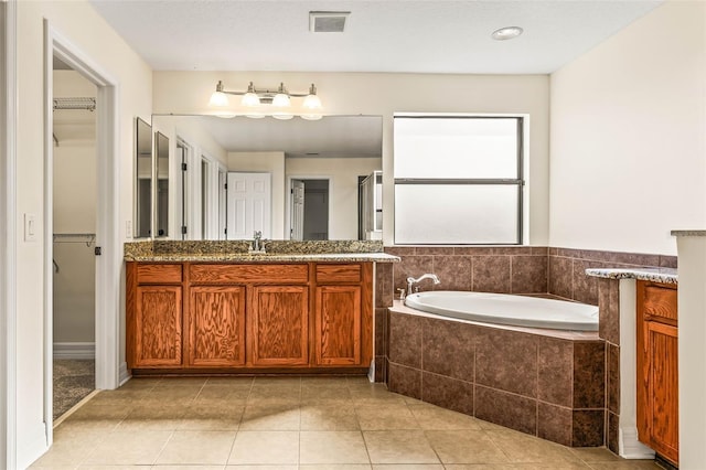 bathroom with vanity, tiled tub, and tile patterned floors