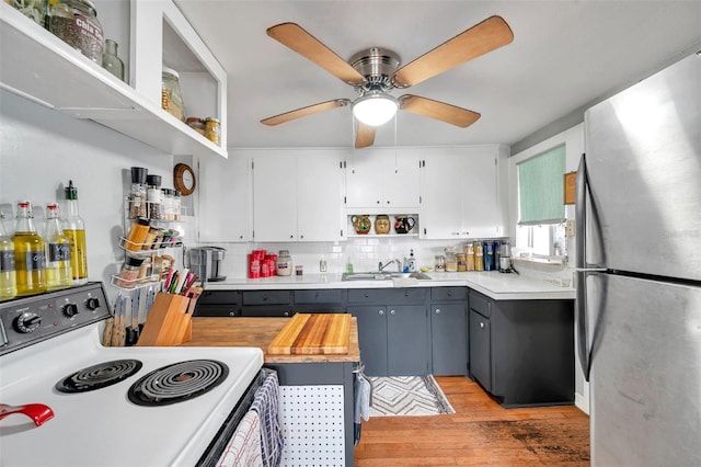 kitchen with white electric stove, tasteful backsplash, gray cabinetry, white cabinets, and stainless steel fridge