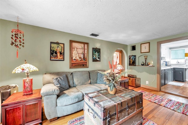 living room with a textured ceiling and light hardwood / wood-style flooring