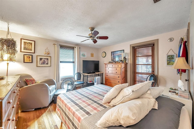 bedroom with hardwood / wood-style flooring, a textured ceiling, and ceiling fan